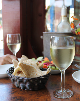image of pita bread on a table with a glass of white wine